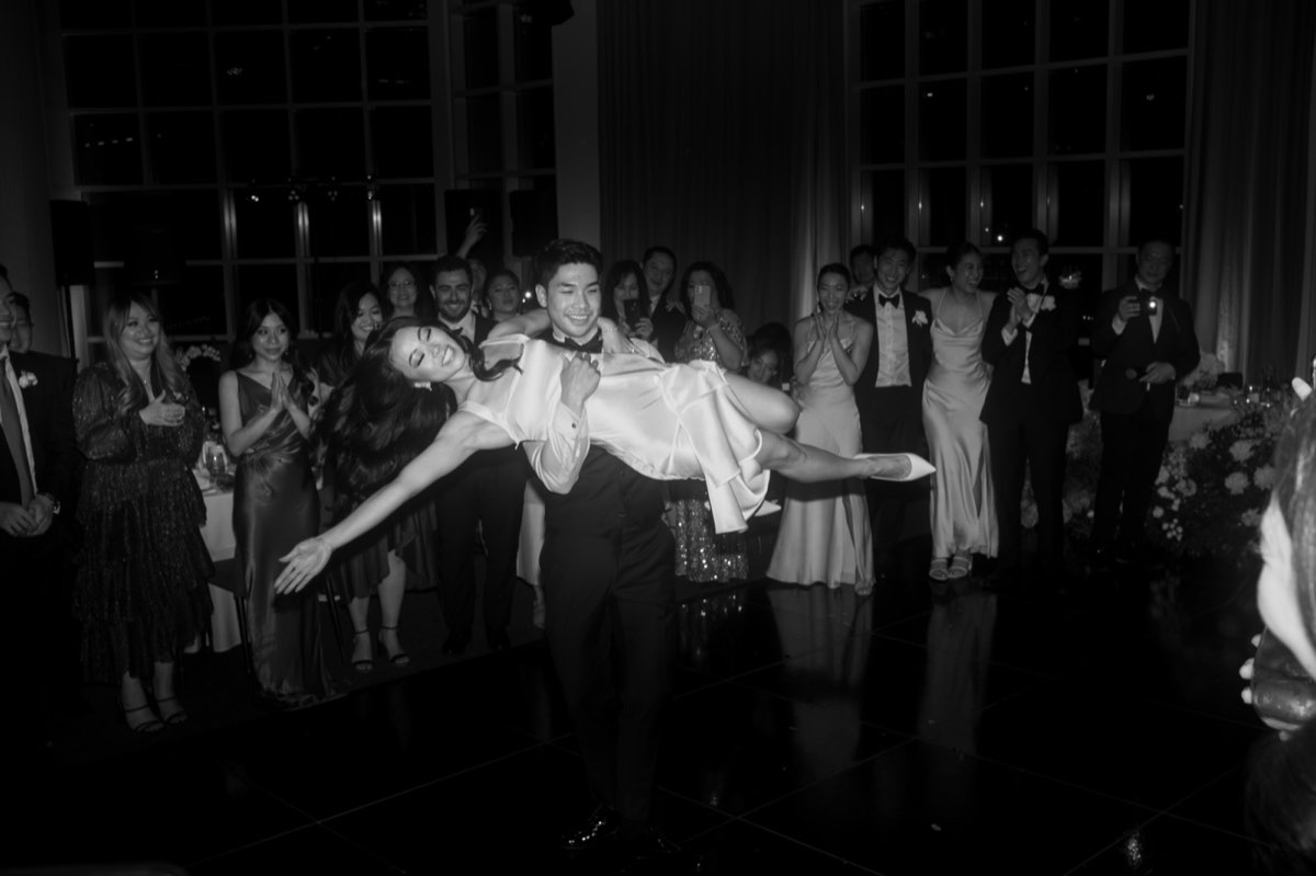 The groom carried horizontally by laughing guests across the dance floor