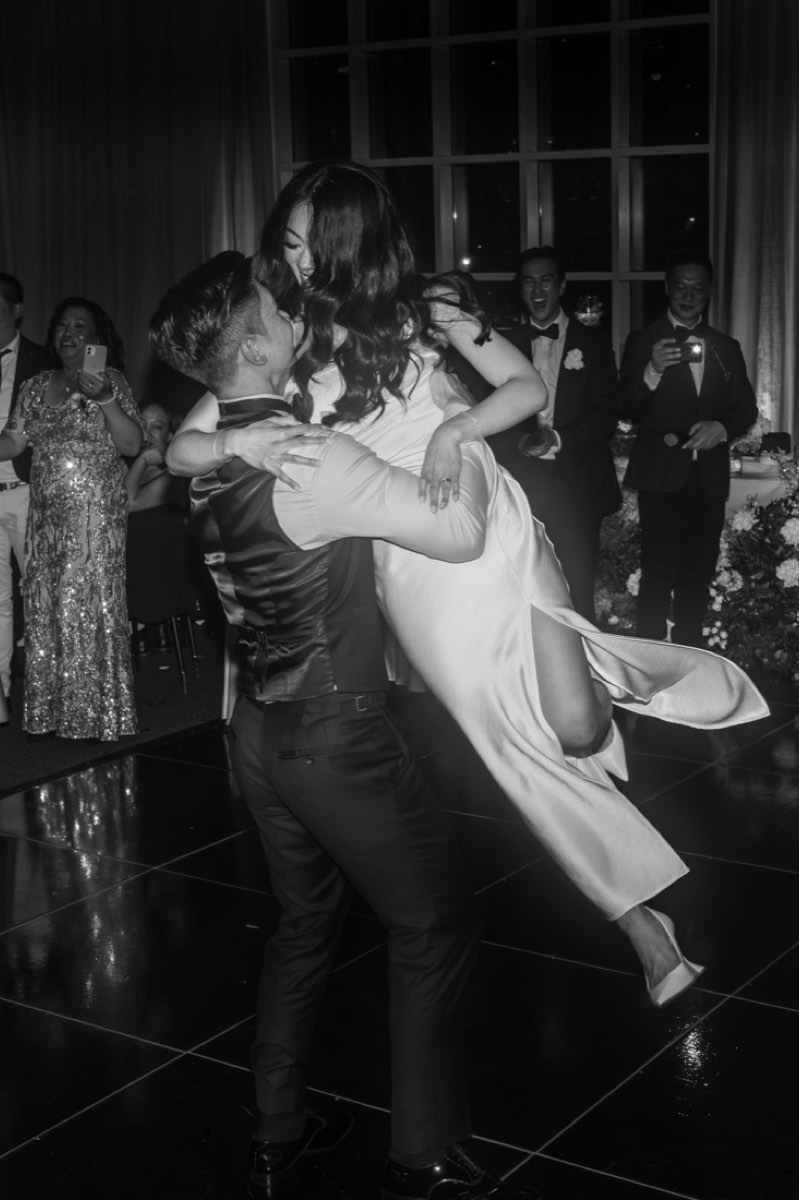 The groom lifts the bride off her feet in the middle of the dance floor