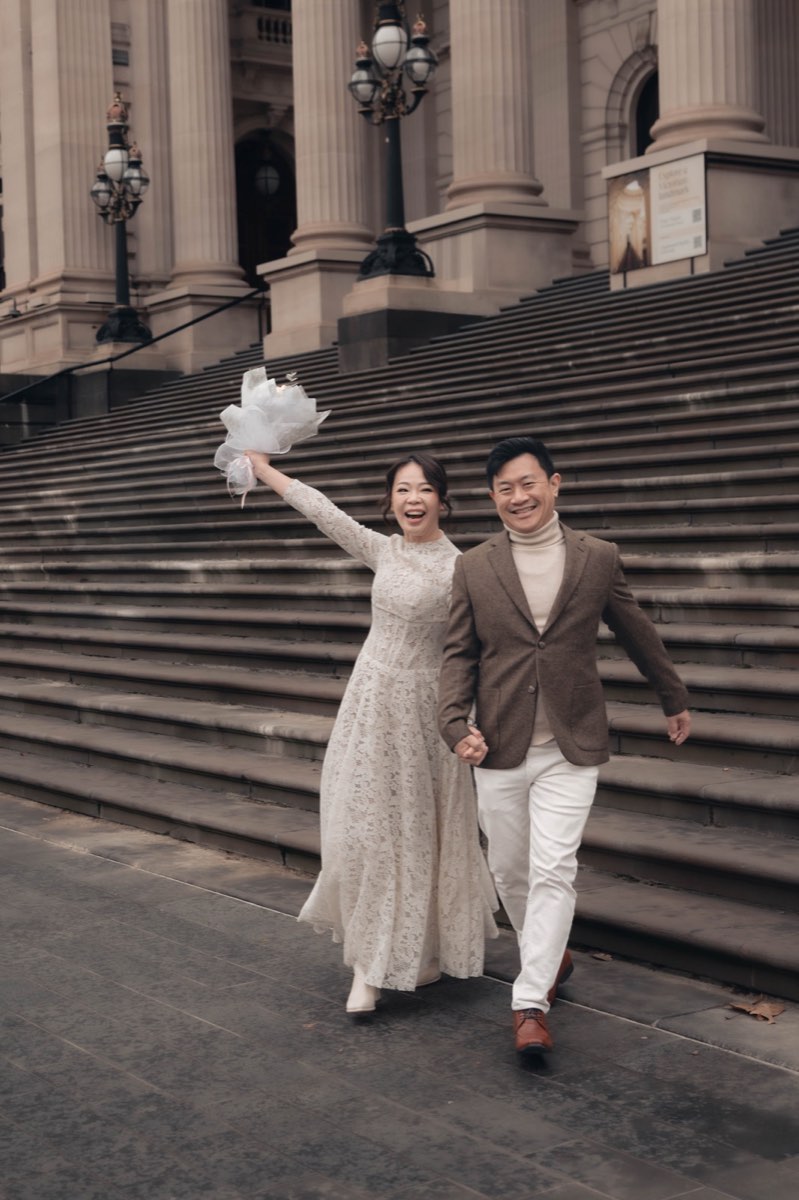 The couple run down the Parliament steps together, bouquet held high