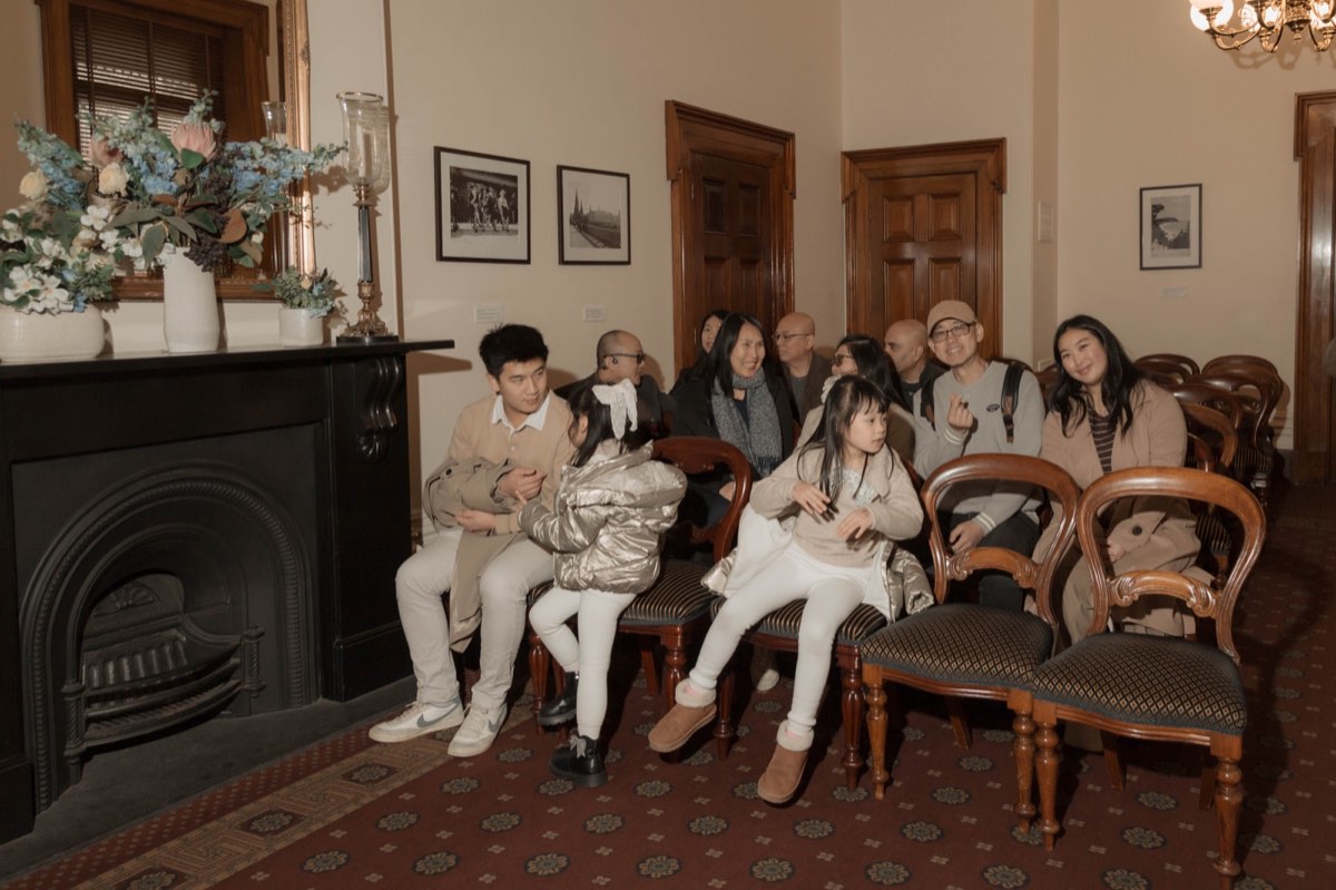 Family and friends wait on antique chairs beside a fireplace before the ceremony